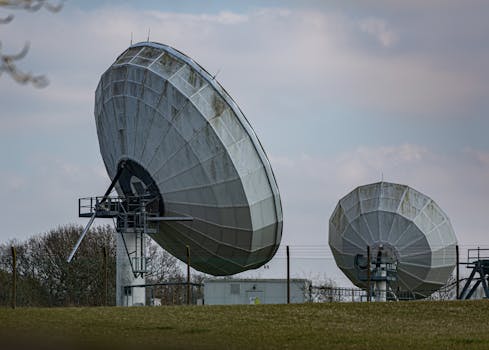 Two large radio telescopes in an outdoor setting, showcasing astronomy and science technology.